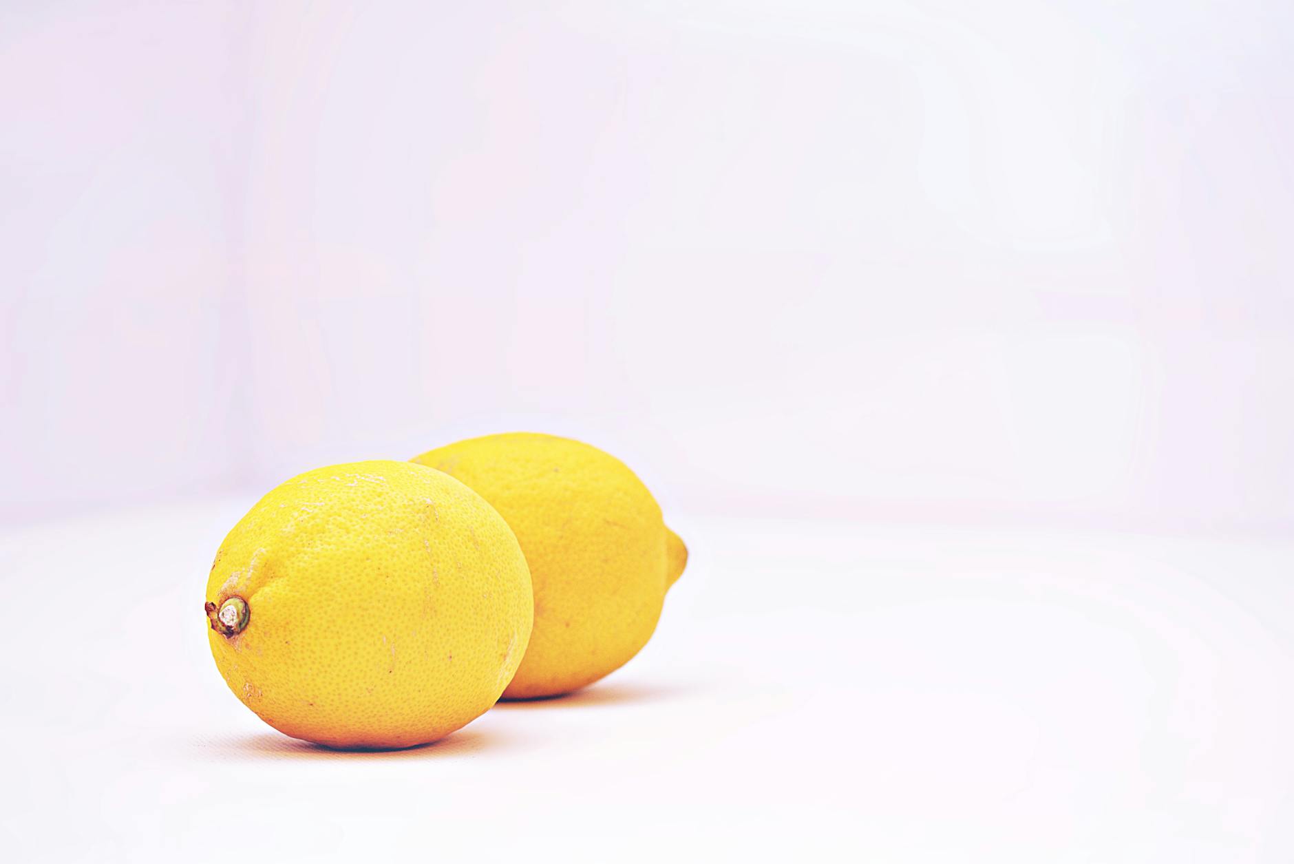 Dos limones vibrantes colocados sobre un fondo blanco minimalista, simbolizando frescura y placer clitoral