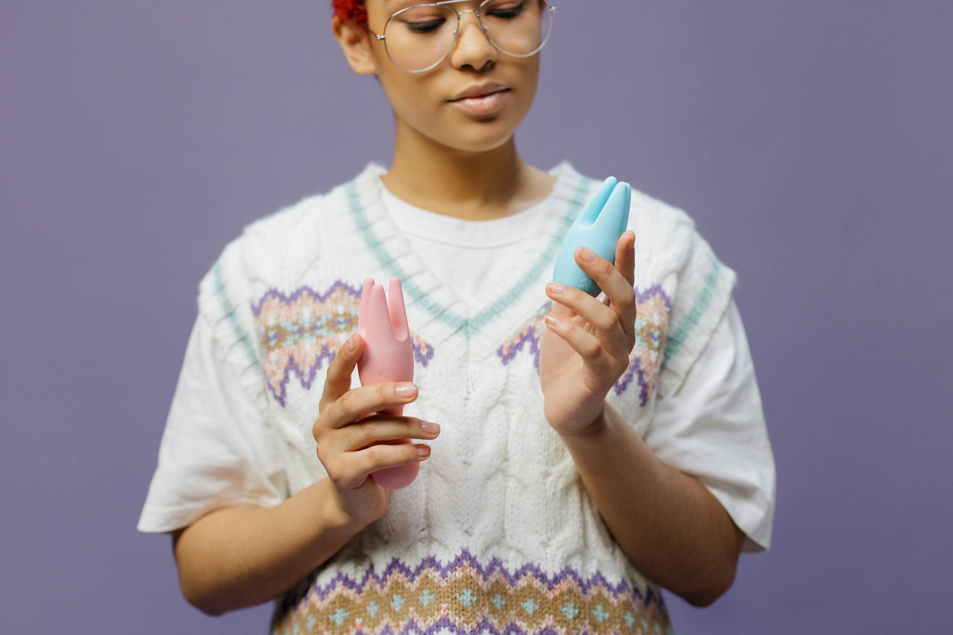Woman holding colorful silicone vibrators in a thoughtful moment during recovery