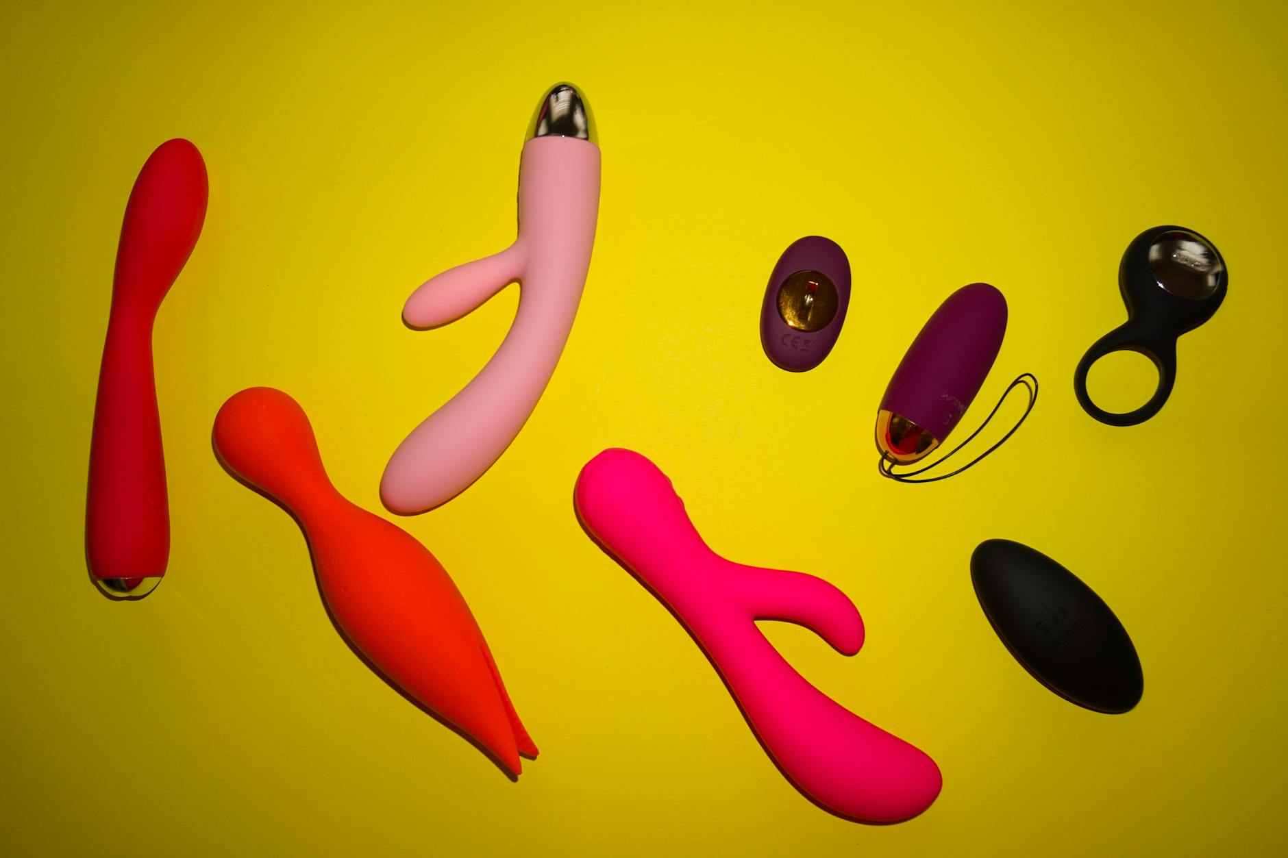 Close-up of a hand holding a pink vibrator with art books in the background